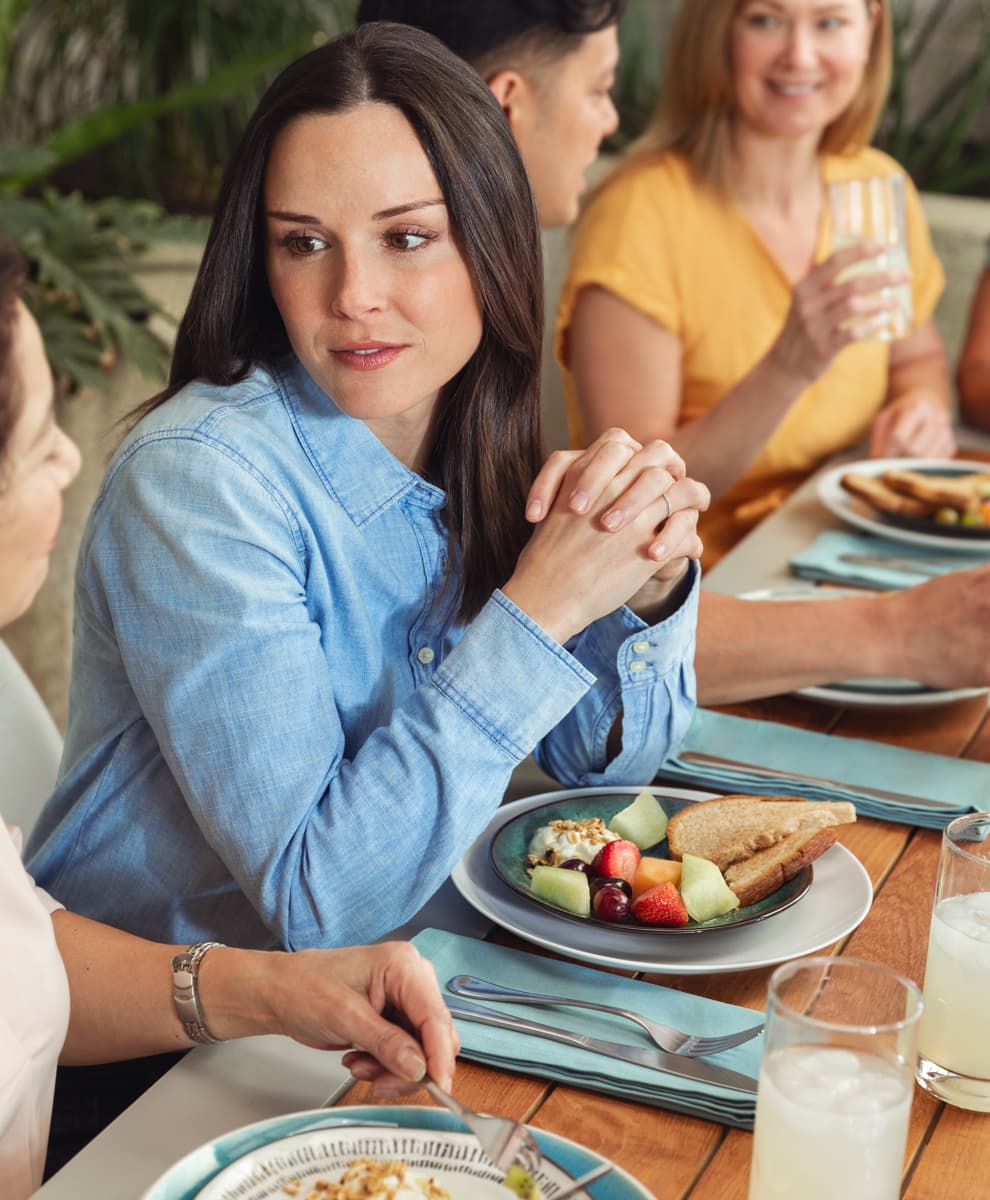 Woman eating breakfast talking to family and friends